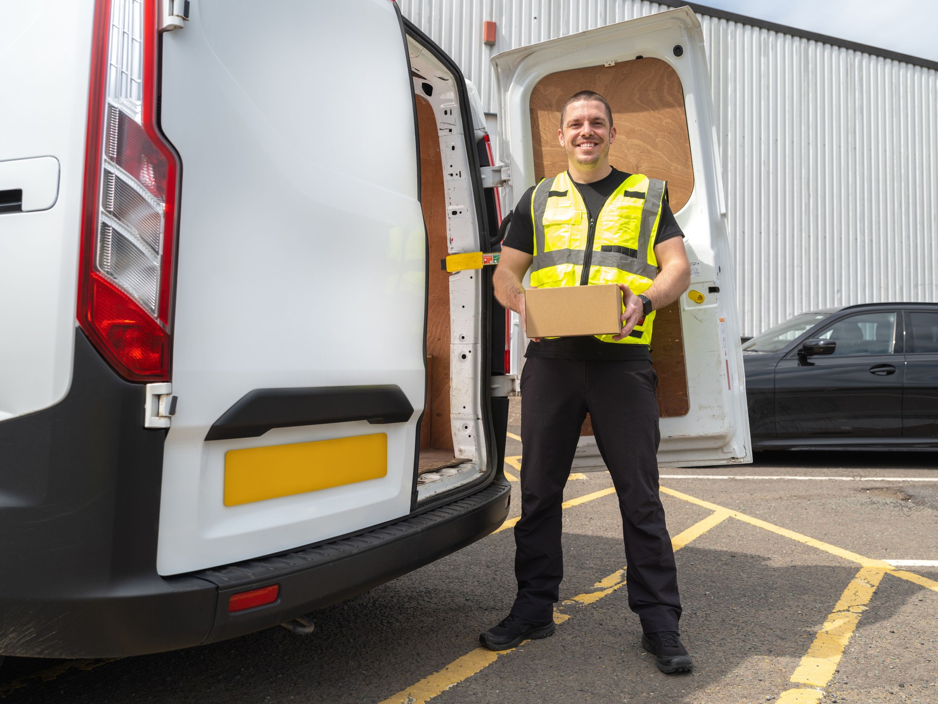 Friendly Van Driver Holding Parcel Next Too Delivery Van
