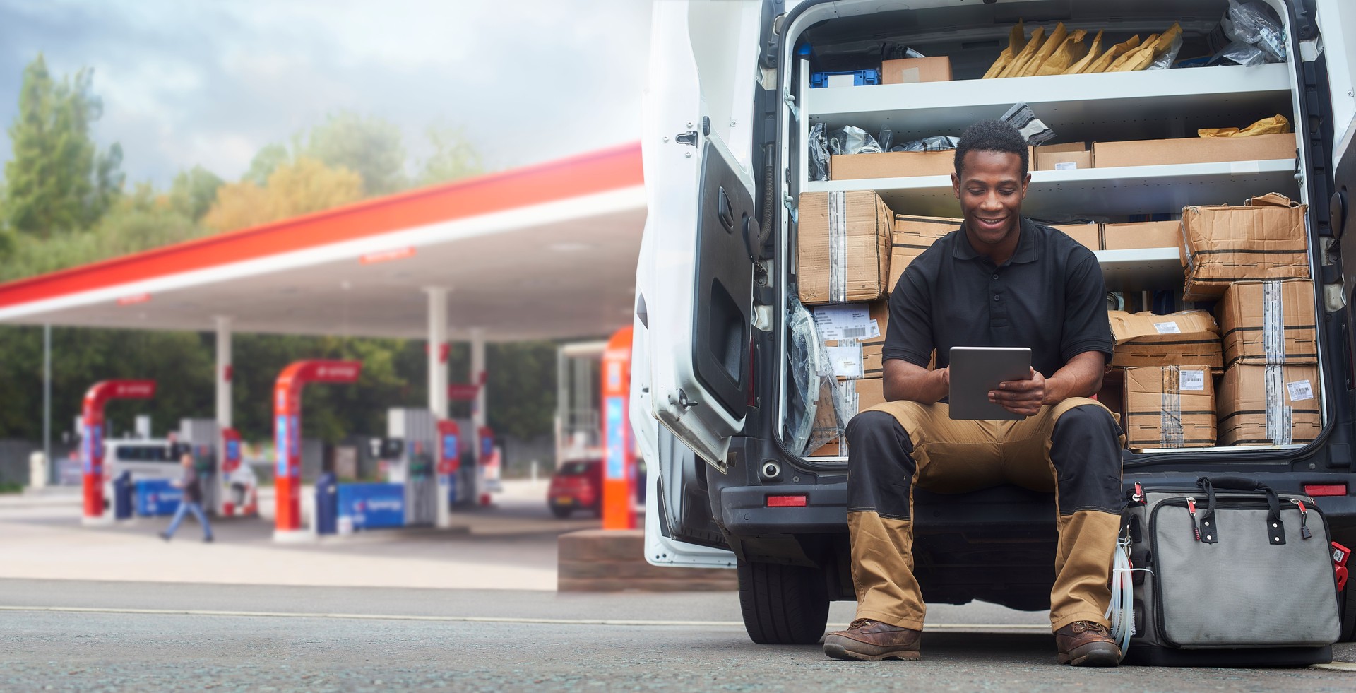 Service engineer sat on the back step of his van